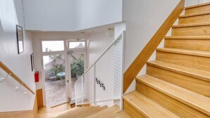 A staircase with wooden steps and white railings leading to an outdoor area with a glass door. - Cute & Bright Studio in a Courtyard-Montmartre(5) (Paris)