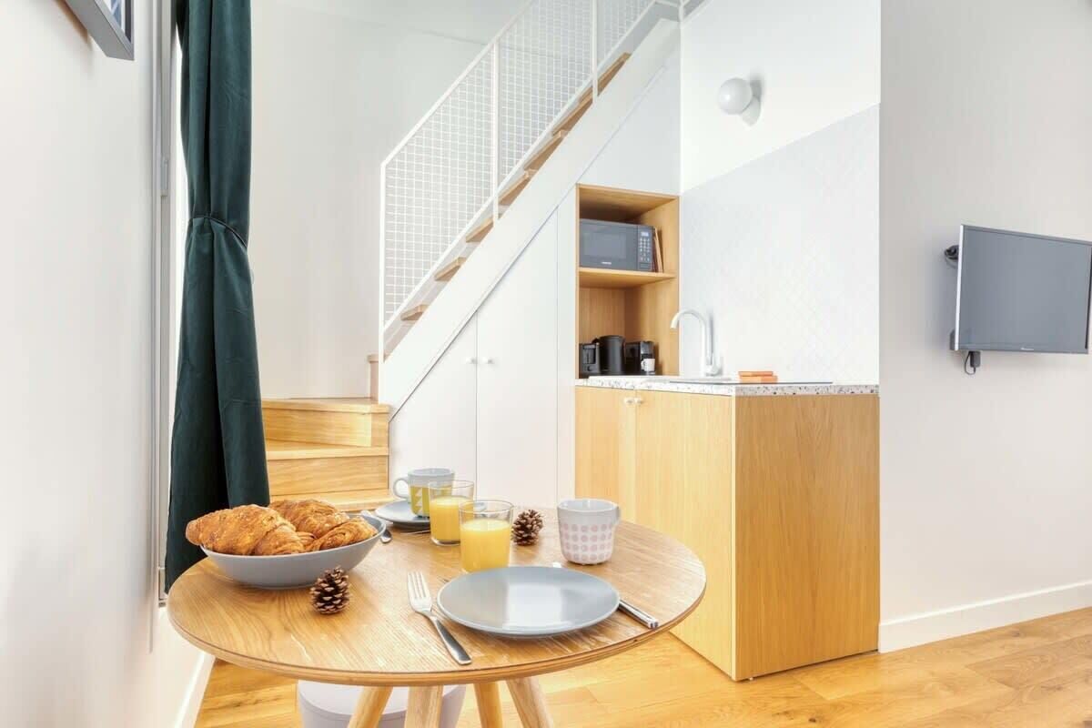 Una cocina compacta con comedor, microondas y un lavamanos pequeño.