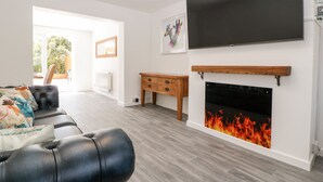 Ein modernes Wohnzimmer mit Kamin, Flachbildfernseher und Holzschrank.