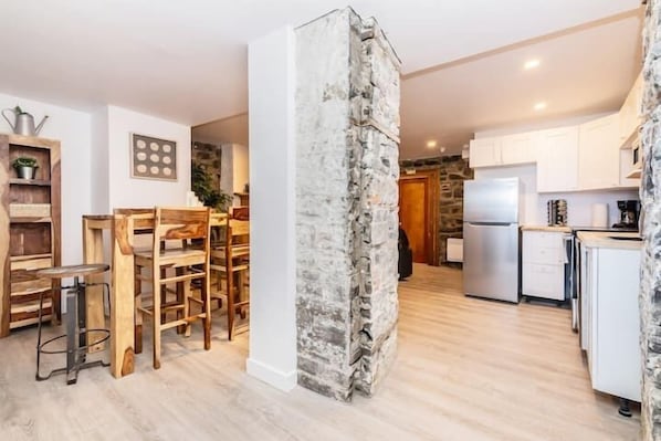 Una cocina moderna con armarios blancos, un refrigerador integrado y una pared decorativa de piedra.