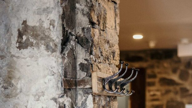 A rustic interior with a stone wall and a metal coat rack. - Modern Meets Rustic - 2 Bdrm Old Quebec (Québec City)