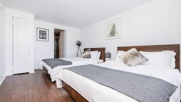 Et soveværelse med to senge, en dør, en lampe og billeder på væggene.