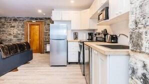 A compact kitchen with white cabinets, a stainless steel refrigerator, and a microwave. - Modern Meets Rustic - 2 Bdrm Old Quebec (Québec City)