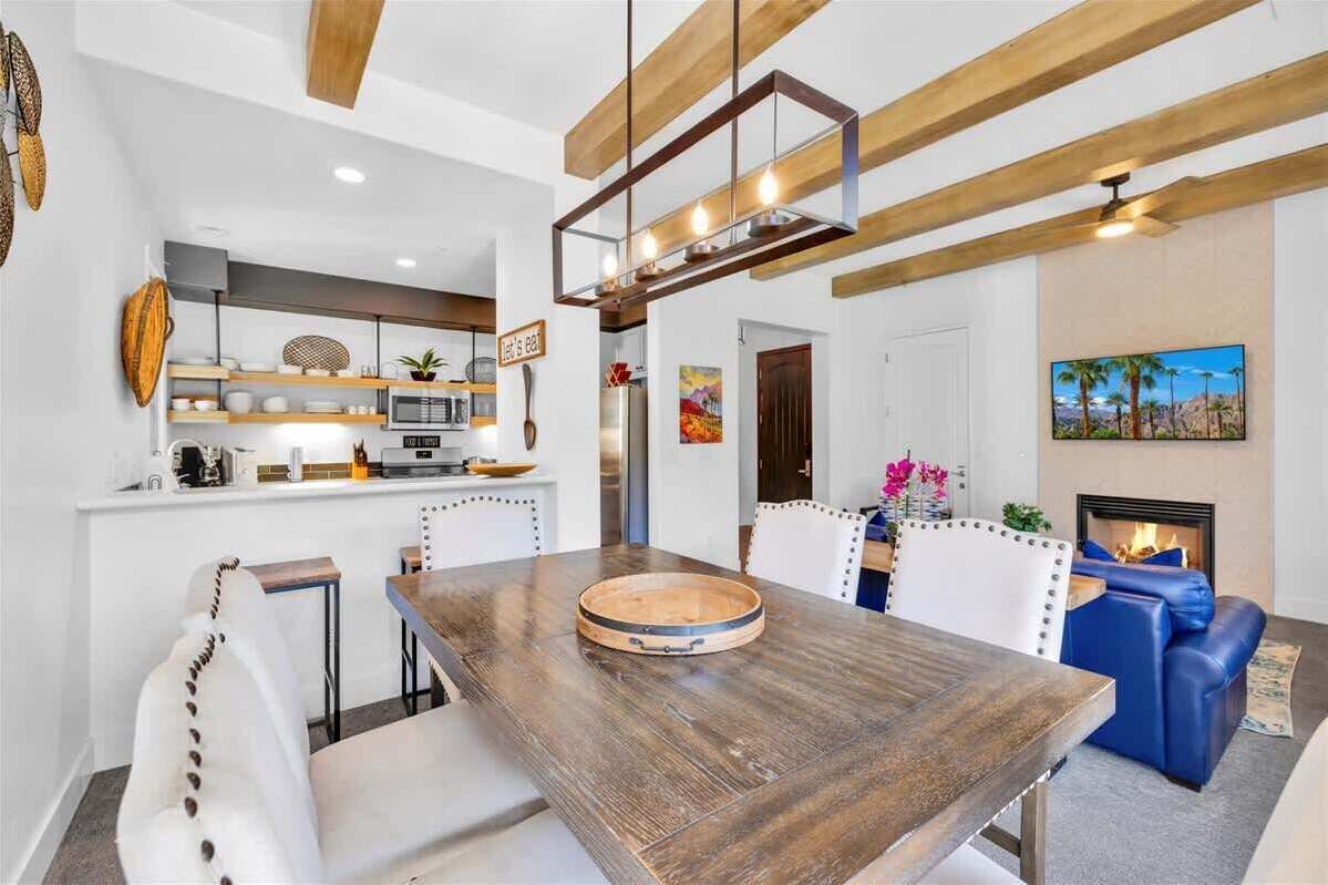 A modern kitchen with white cabinetry, a wooden dining table, and a blue sofa in the living area.