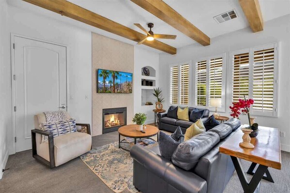 A living room with a fireplace, a sofa, a coffee table, and a ceiling fan.