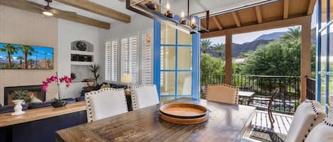 A modern dining area with a wooden table, white chairs, and a blue-framed window.
