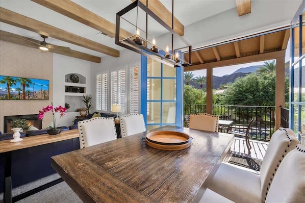 A modern dining area with a wooden table, white chairs, and a blue-framed window.