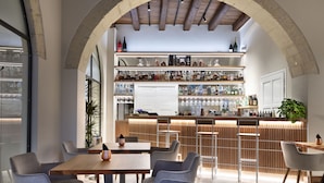 A restaurant with a bar area, wooden tables, and chairs. - Casa Clàt – Boutique Hotel (Cagliari)