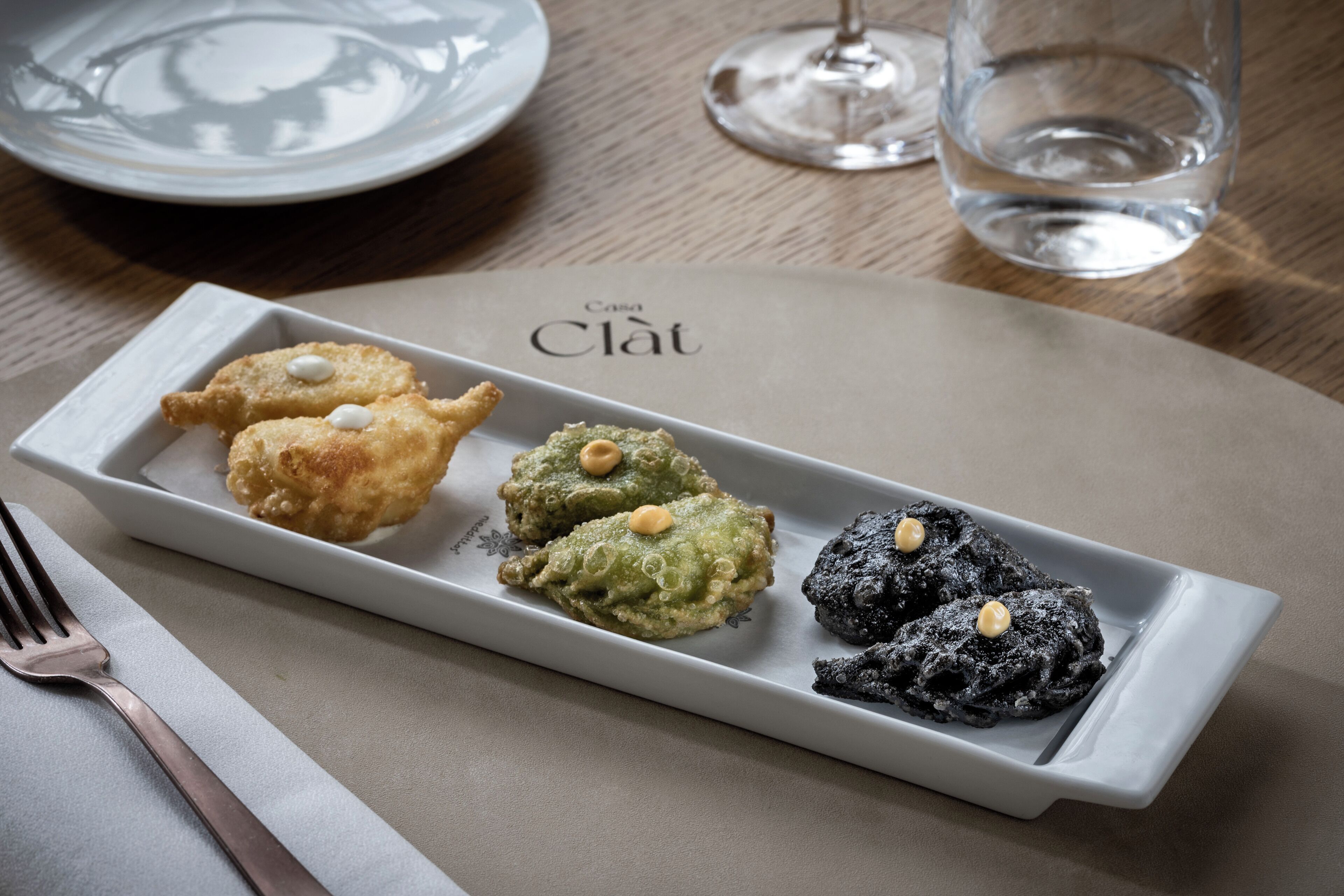 A rectangular white plate with four pieces of food on a table.