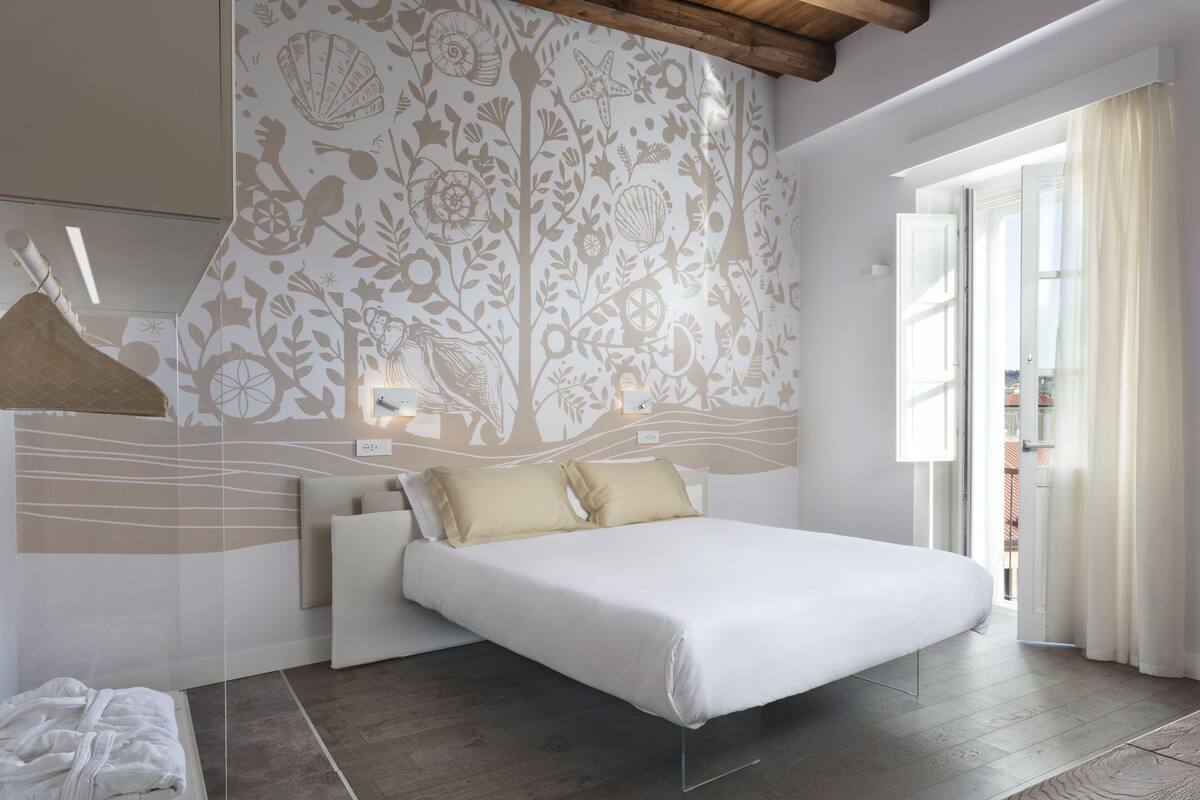Ein modernes Schlafzimmer mit einem großen Bett, einer Wanddekoration und Blick durch eine offene Tür.