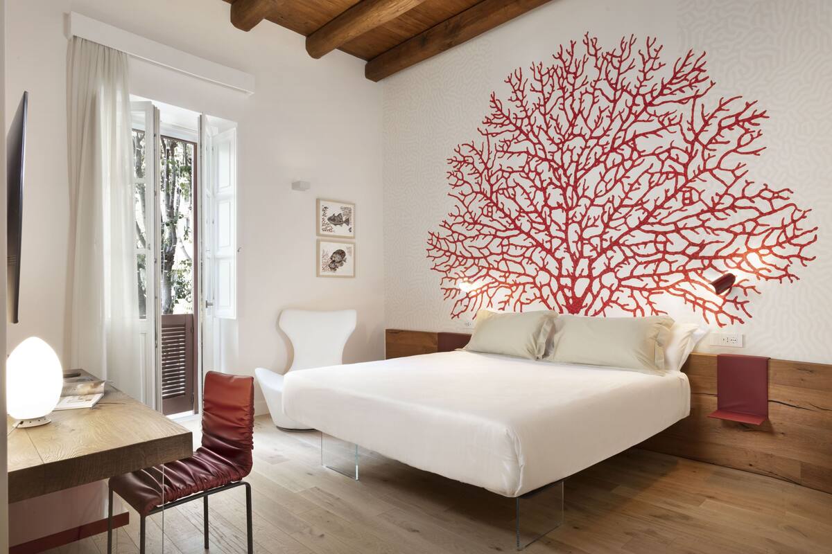 Ein Schlafzimmer mit einem Bett, einem Schreibtisch, einem Stuhl und einem großen Wandbild.