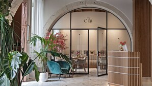 An interior with a reception desk, a dining area, and a large arched doorway. - Casa Clàt  – Boutique Hotel (Cagliari)