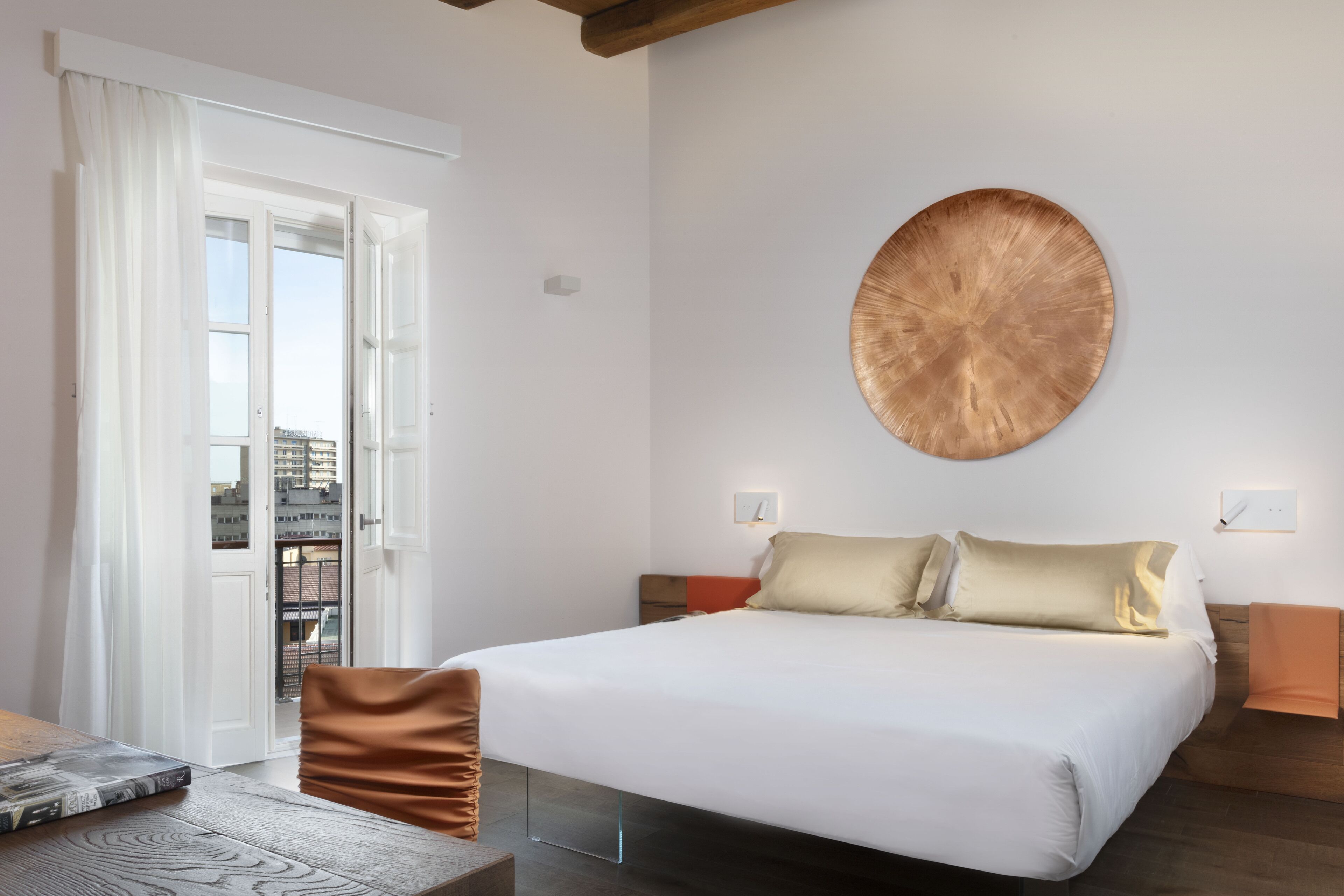 Una camera da letto moderna con un letto grande, una decorazione rotonda a parete e vista attraverso una porta aperta.