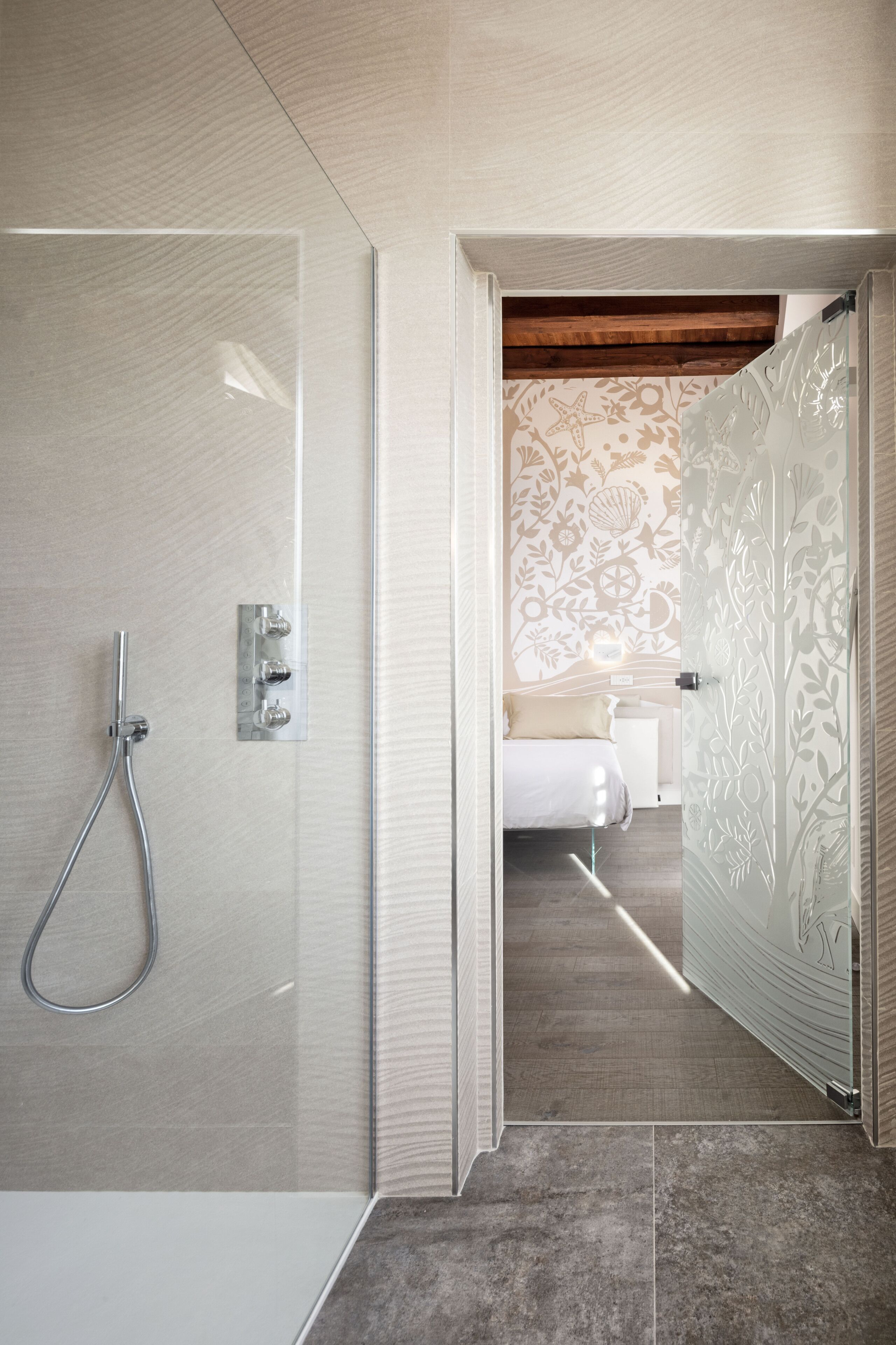 A modern bathroom with a glass shower enclosure, a wooden ceiling, and a patterned wall.
