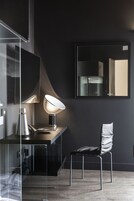 A modern office space with a desk, chair, lamp, and large mirror.