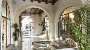 A spacious lobby with arched ceilings, a glass coffee table, and a seating area with a sofa and armchairs. - Casa Clàt – Boutique Hotel (Cagliari)