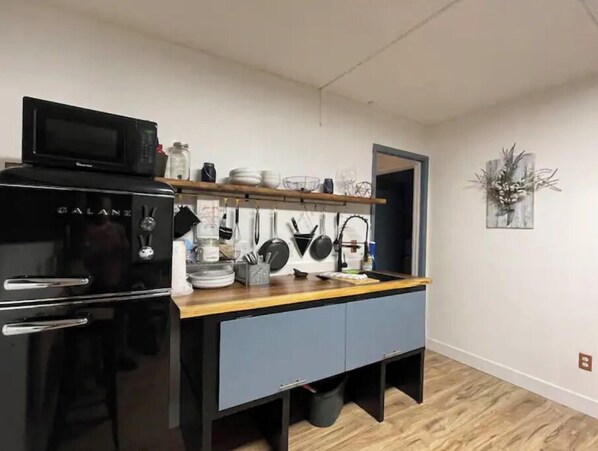 Fully equipped kitchen with refrigerator, microwave, sink, and ample storage for cookware and utensils.
