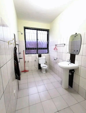 Et badeværelse med toilet, vask og et vindue med tremmer.