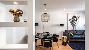 A modern living room with a dining area, featuring a round table, black chairs, a dark sofa, and a large abstract painting. - Keluak Apartment, Wifi, Balcony !new! (Lisboa)