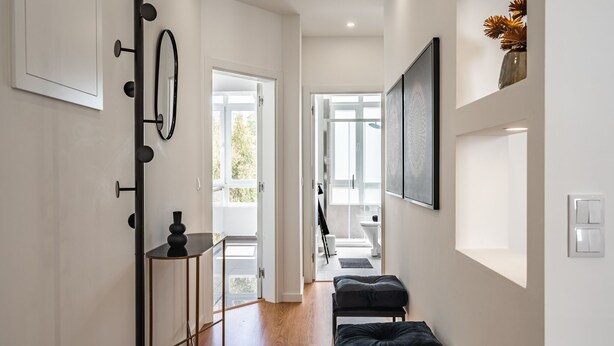 A hallway with a mirror, a black bench, and a door leading to a bathroom. - Keluak Apartment, Wifi, Balcony !new! (Lisboa)