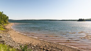 A beach with a rocky shoreline and calm water. - Woodhaven Country Lodge (Oak Bay)