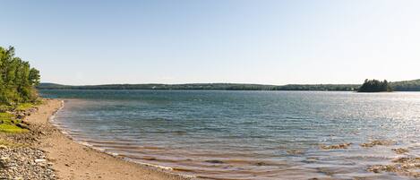 A beach with a rocky shoreline and calm water.