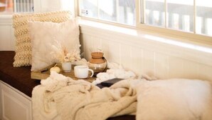Ein gemütliches Zimmer mit einem großen Fenster, einer gepolsterten Bank und einem kleinen Tisch mit Teekanne und Tassen.