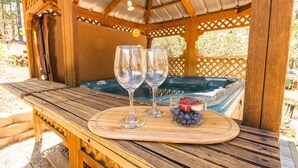 Ein Holz-Sitzbereich im Freien mit zwei Weingläsern und einer Schüssel Beeren.