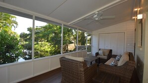 A covered porch with wicker furniture, a ceiling fan, and a view of greenery. - Canal View 2BR Retreat, Near Bonita Beach! Sleeps 4 (Bonita Springs)