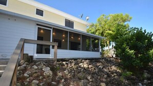 A modern house with a covered porch, large windows, and satellite dishes. - Canal View 2BR Retreat, Near Bonita Beach! Sleeps 4 (Bonita Springs)