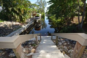 A wooden staircase leading down to a body of water, surrounded by trees and rocks.