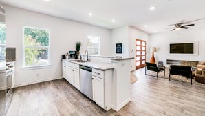 Una cocina amplia con una isla grande, un comedor con sofá y sillas, y un ventilador de techo.