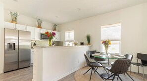 A modern kitchen with white cabinets, a stainless steel refrigerator, and a central island with seating.