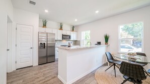 Una cocina moderna con armarios blancos, electrodomésticos de acero inoxidable y una isla central con asientos.