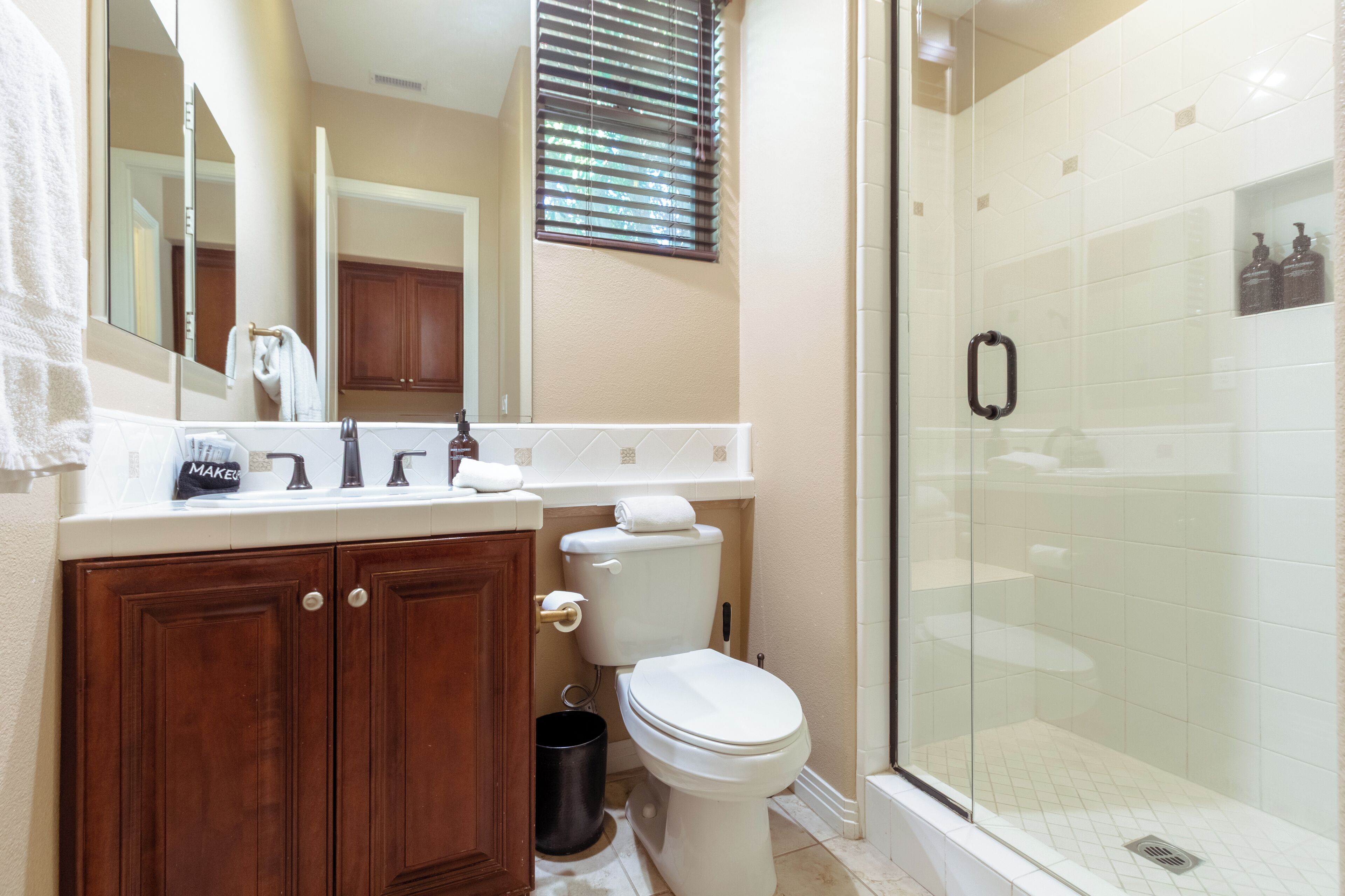 A bathroom with a wooden vanity, white toilet, and a glass-enclosed shower.