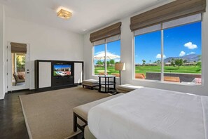 Ein Hotelzimmer mit einem großen Bett, einem Fernseher, einem kleinen Tisch und Blick auf einen Golfplatz.