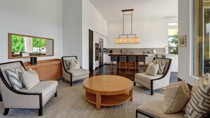 Een moderne woonkamer met een ronde houten salontafel, twee banken en een keuken op de achtergrond.