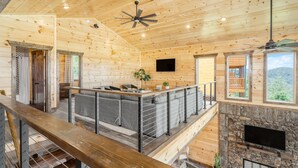 Een houten cabin met een zithoek, een stenen open haard en een balkon met uitzicht.