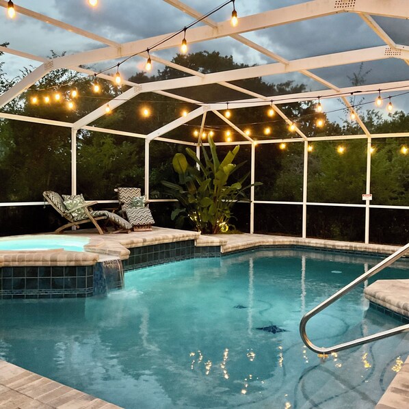 A pool area with a glass enclosure, string lights, and lounge chairs. - Private Heated Pool and Hottub , Pet Friendly, New Golf Cart , Close to shopping (Lady Lake)