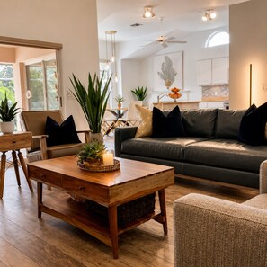 Una sala de estar moderna con una mesa de centro de madera, sofá de cuero y una zona de comedor con una silla y mesa.