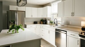 Een moderne keuken met witte kasten, een roestvrijstalen koelkast, een vaatwasser en een koffiezetapparaat.