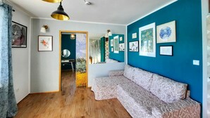 A living room with a blue accent wall, a patterned sofa, and artwork. - Deerwood- 2 Storey Beautiful Relax Garden Bled Castle View Apartment (Radovljica)