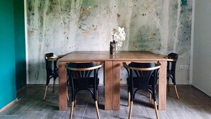 A dining area with a wooden table and four chairs, a vase with flowers, and a textured wall. - Deerwood- 2 Storey Beautiful Relax Garden Bled Castle View Apartment (Radovljica)