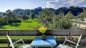 A table with a vase of yellow flowers, a wooden bench, and a view of a castle on a hill. - Deerwood- 2 Storey Beautiful Relax Garden Bled Castle View Apartment (Radovljica)