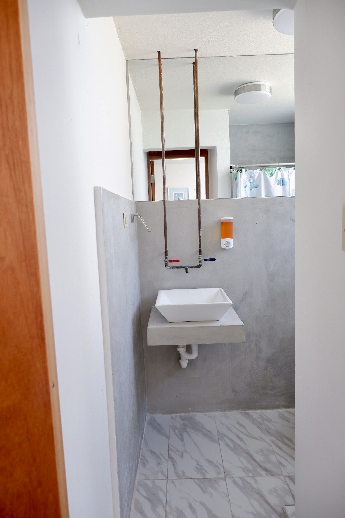 Een badkamer met een wit wastafelmeubel, een spiegel en een douche.