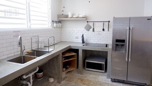 A modern kitchen with a stainless steel refrigerator, a sink with a faucet, and a microwave. - The Emerald (San Juan)
