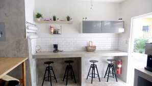 A modern kitchen with white subway tiles, a coffee machine, and two stools. - The Emerald (San Juan)