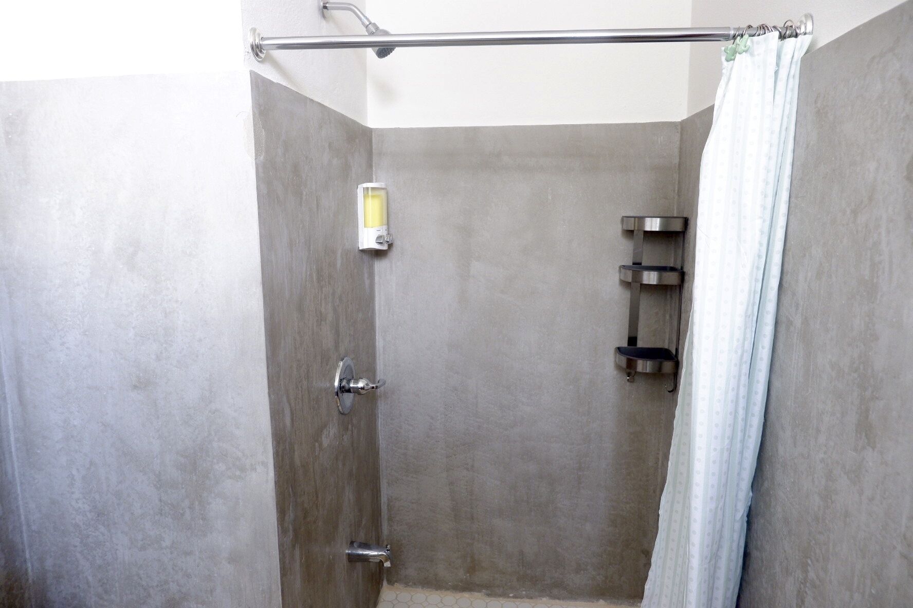 A shower with a glass enclosure, a handheld showerhead, and a towel rack.