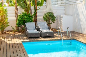 A swimming pool with two wicker lounge chairs and a ladder.