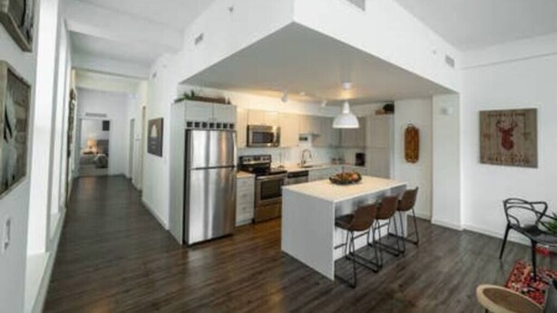 A modern kitchen with a central island, stainless steel appliances, and a dining area with bar stools. - 725- Big 2 bedroom/king beds/Corner Unit/ + parking (Milwaukee)